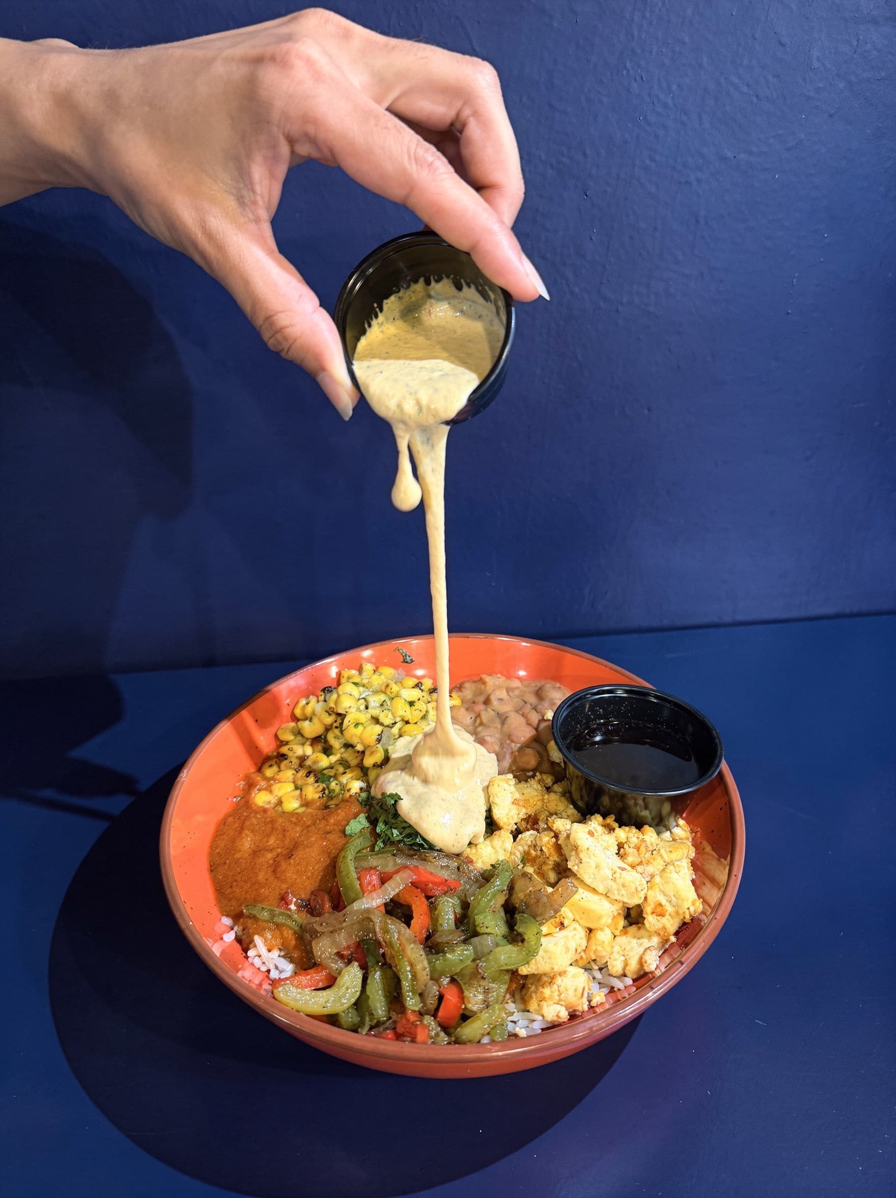 Sauce being poured over fusion bowl