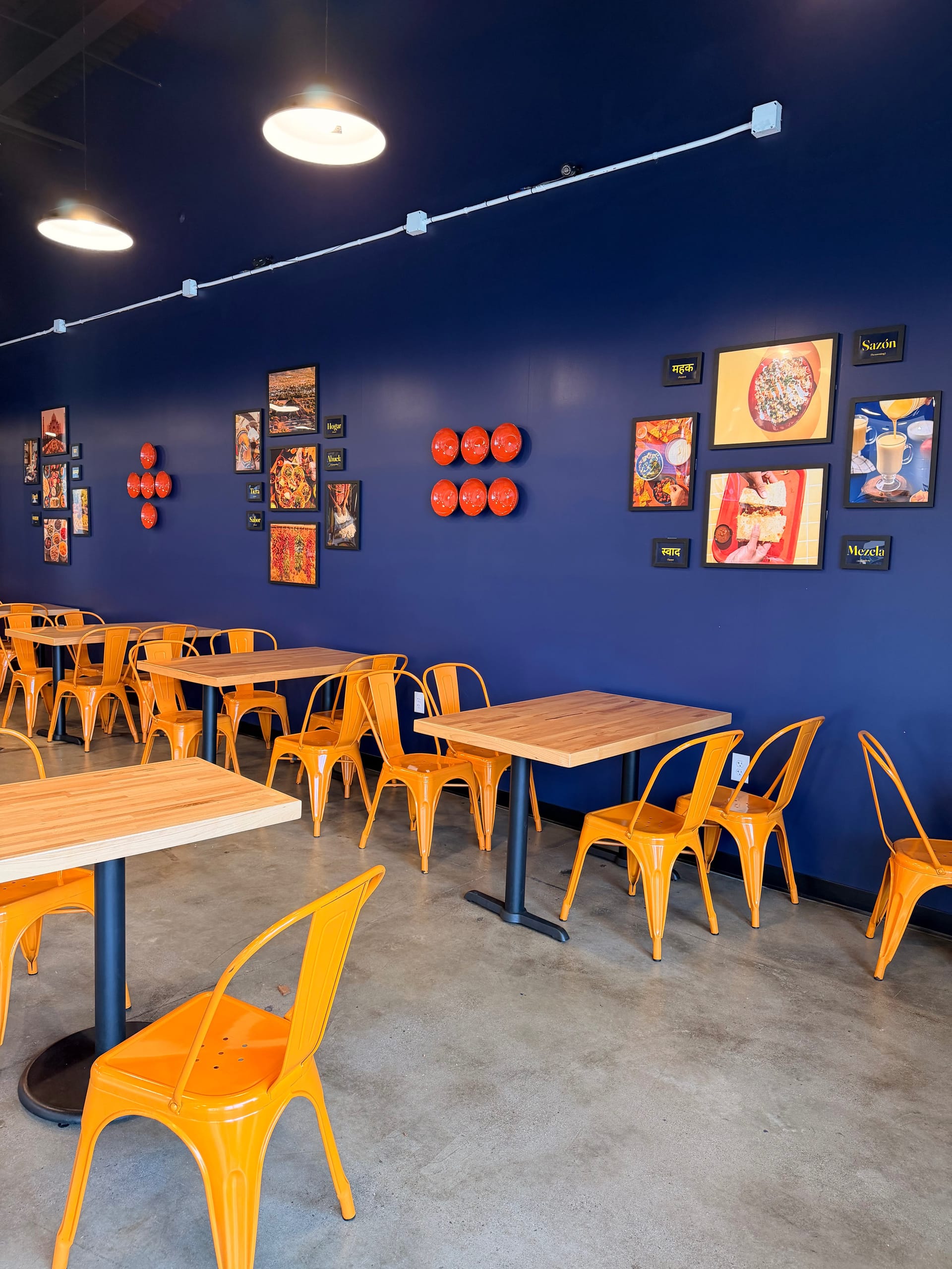 Curry & Queso dining room with navy blue walls and orange chairs